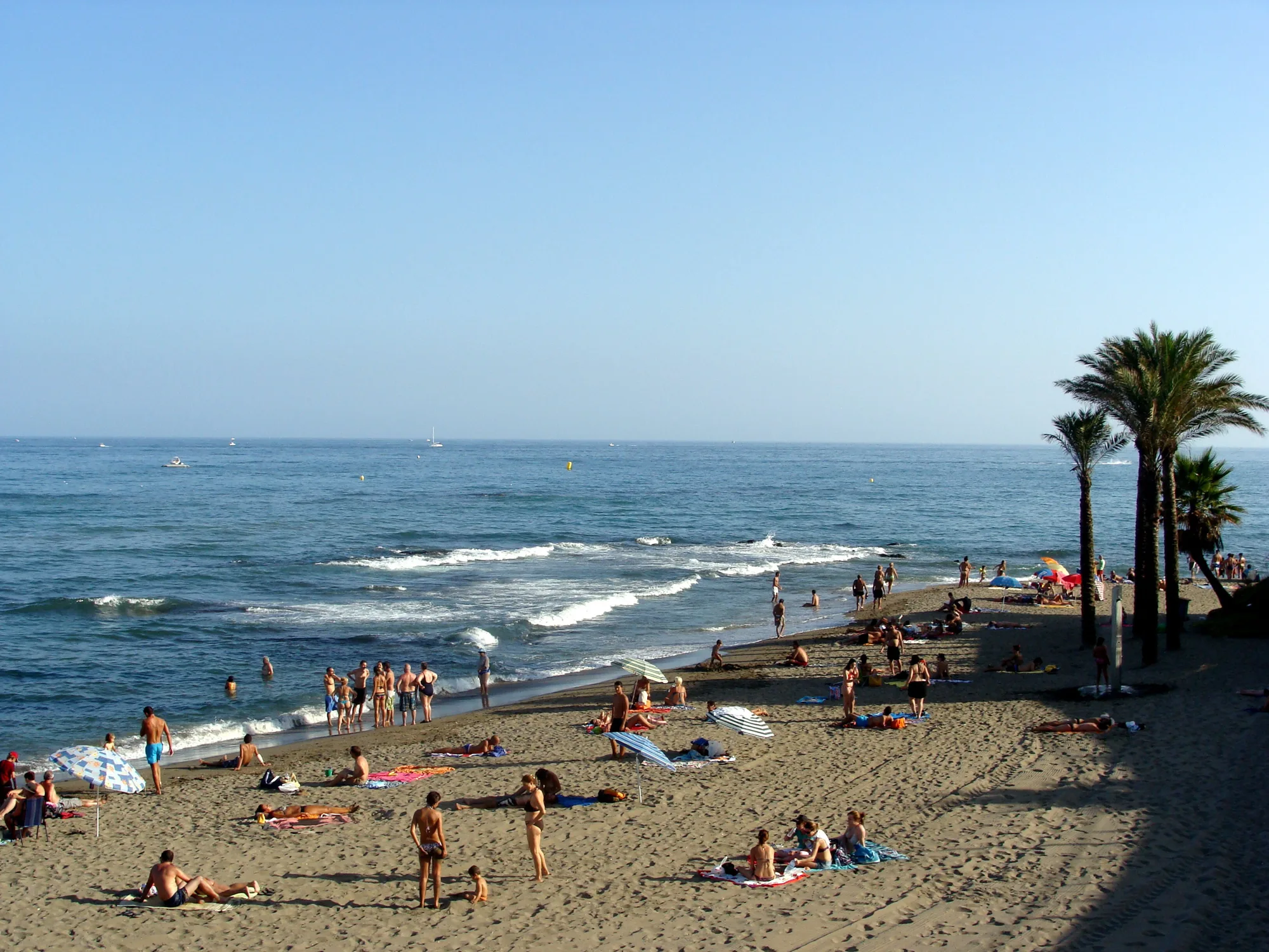Puna plaža na Costa del Sol kod Málage leti: kupači na pesku, palme i talasi